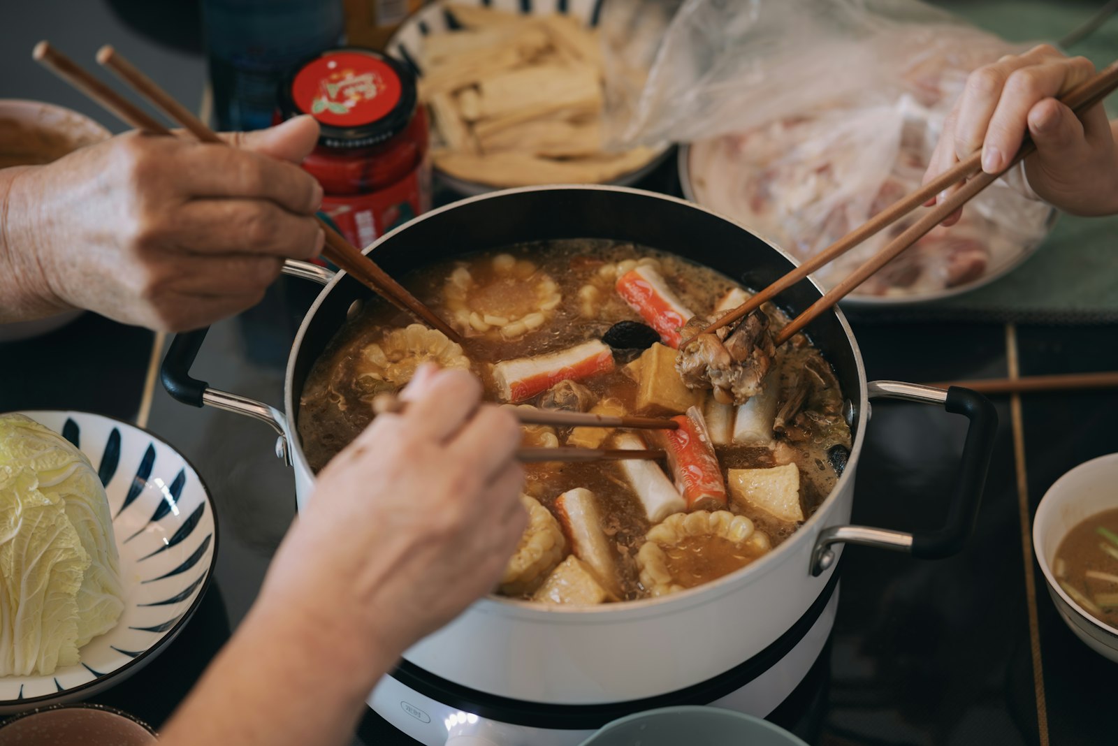 Friends cooking meat and vegetables in a Chinese hot pot at the table