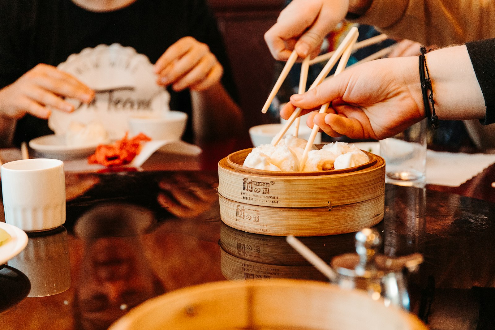 Friends sharing dim sum from bamboo steamers with chopsticks
