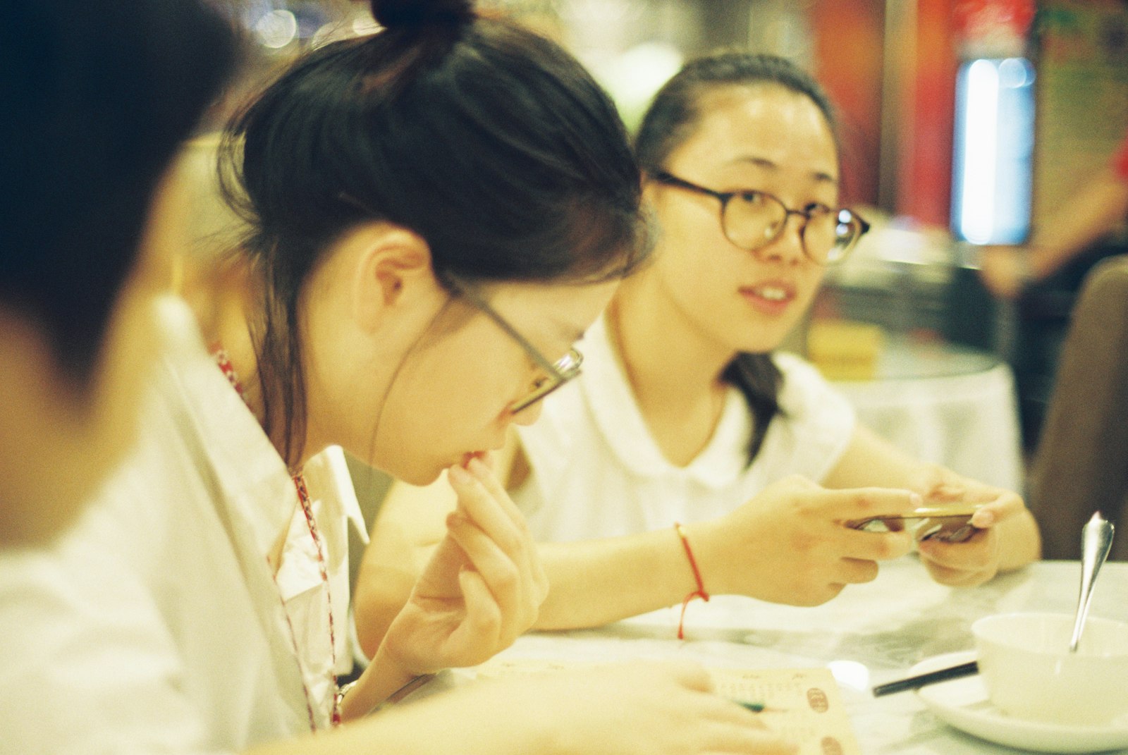 Two friends smiling and sharing dishes at a Chinese restaurant