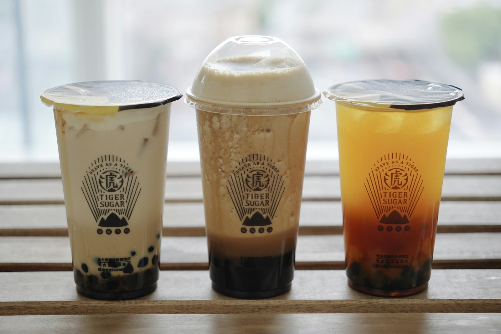Three brown sugar boba milk teas lined up on a counter