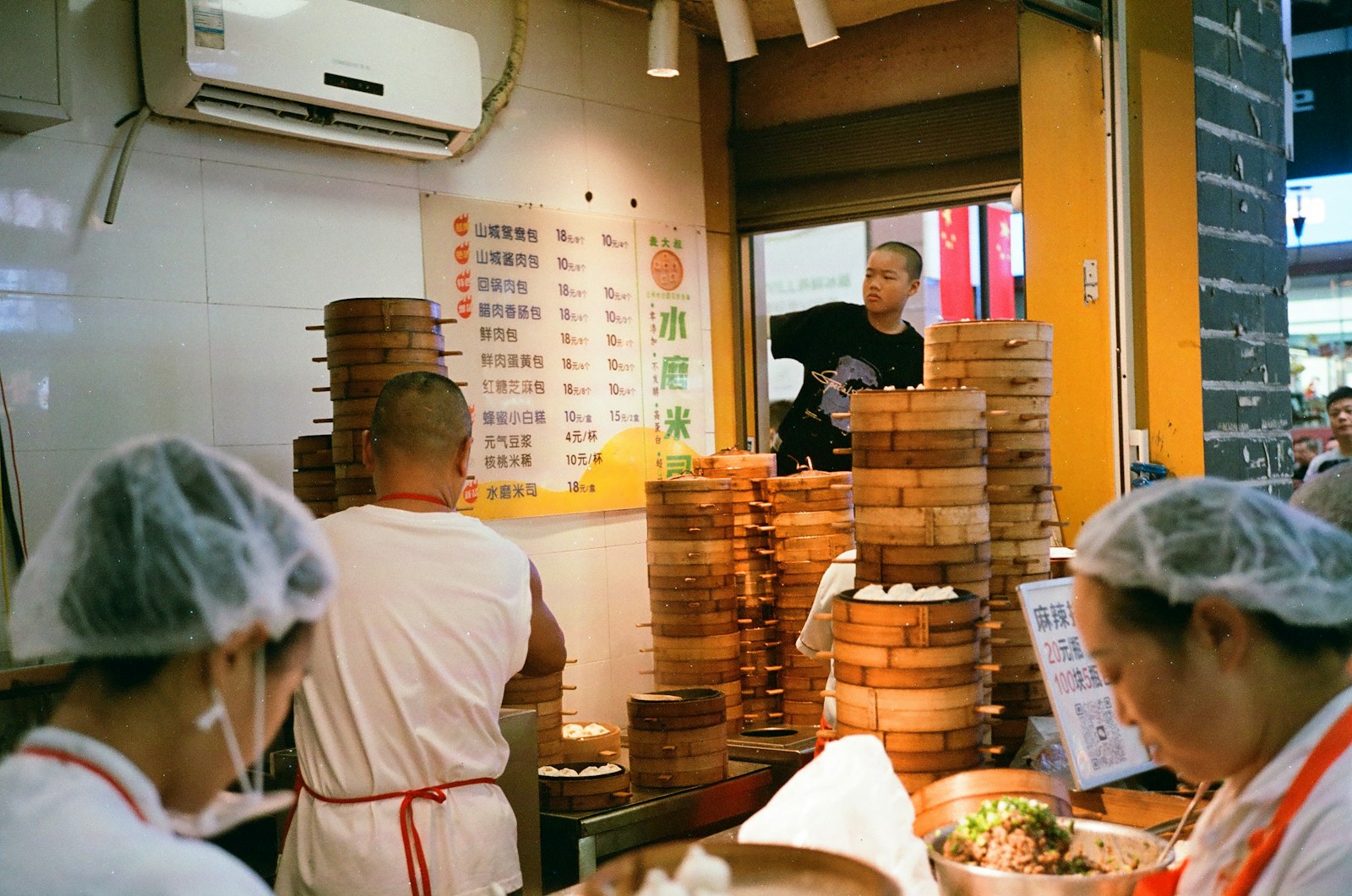 Cooks working in a small dumpling shop with stacks of bamboo steamers