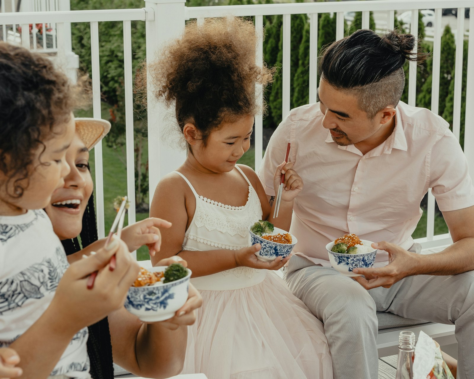 Parents and children eating noodles from bowls with chopsticks
