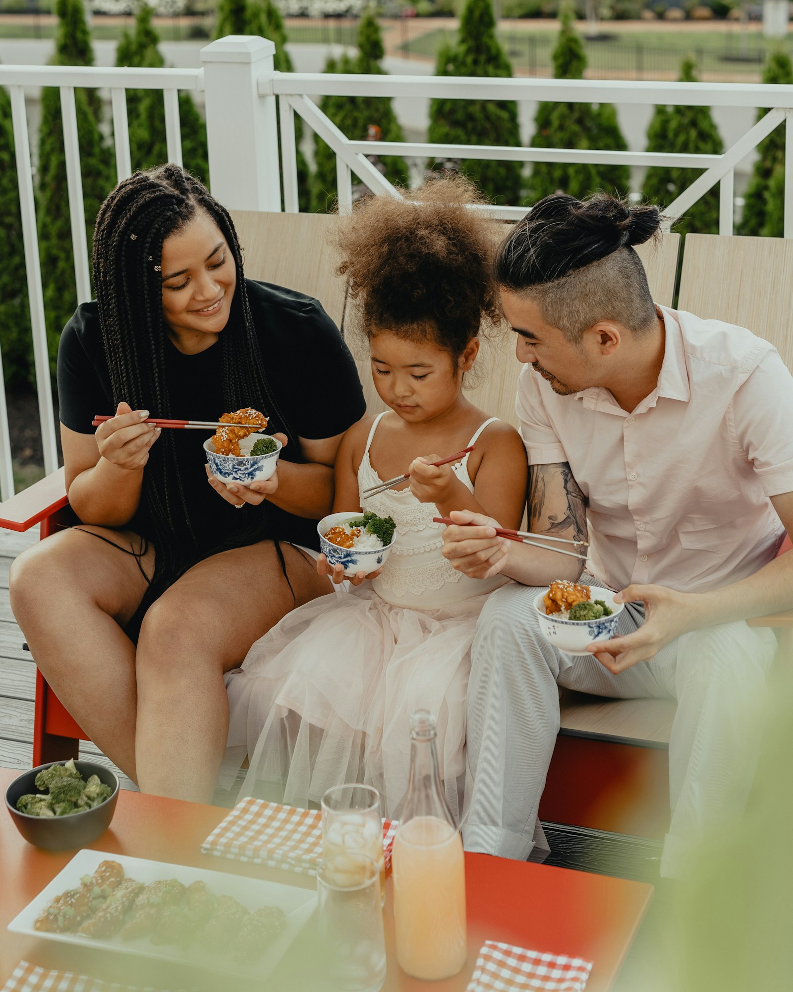 Family sharing Chinese food from takeout bowls with chopsticks