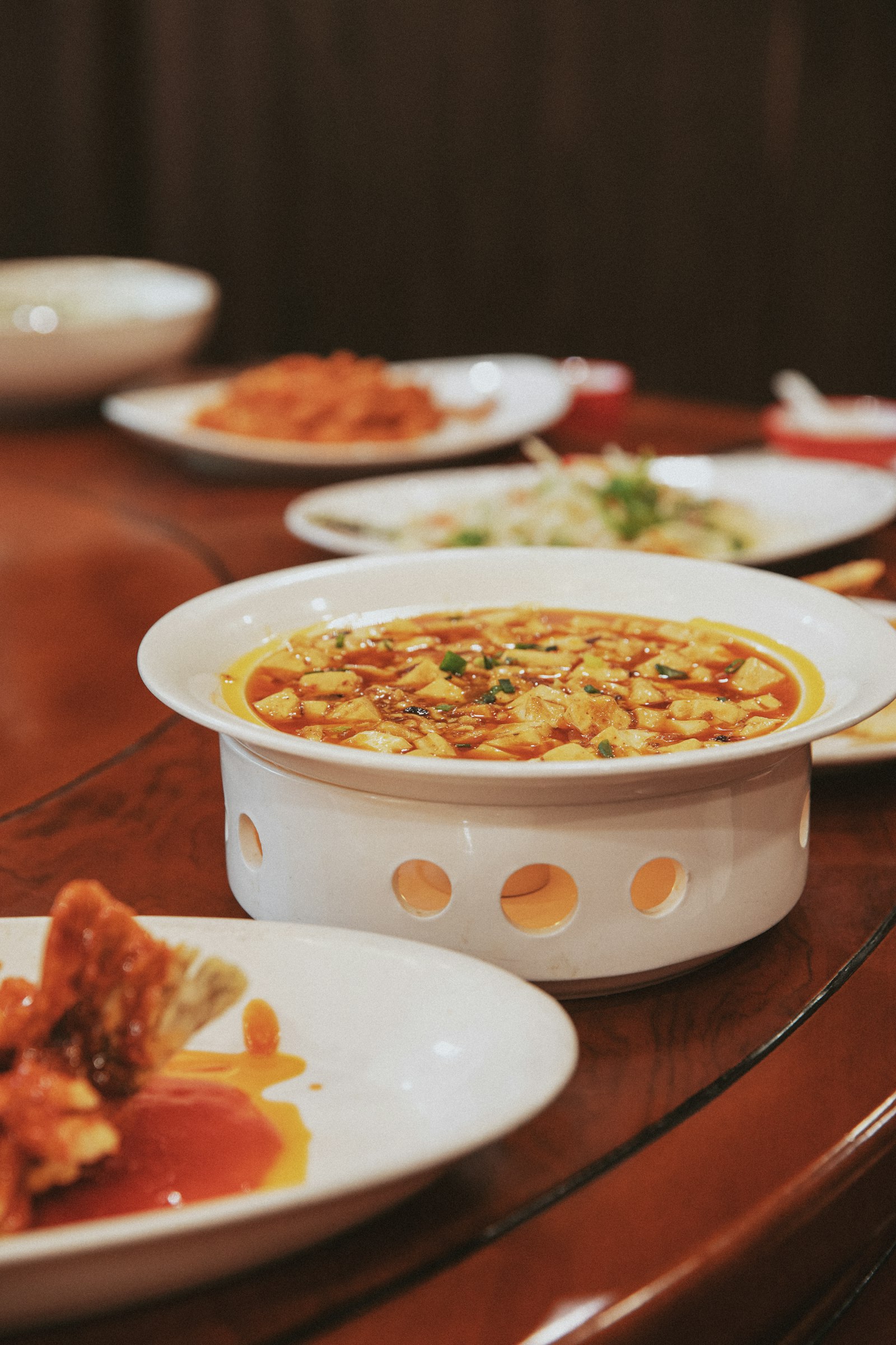 Mapo tofu in red chili sauce kept warm over a tabletop burner
